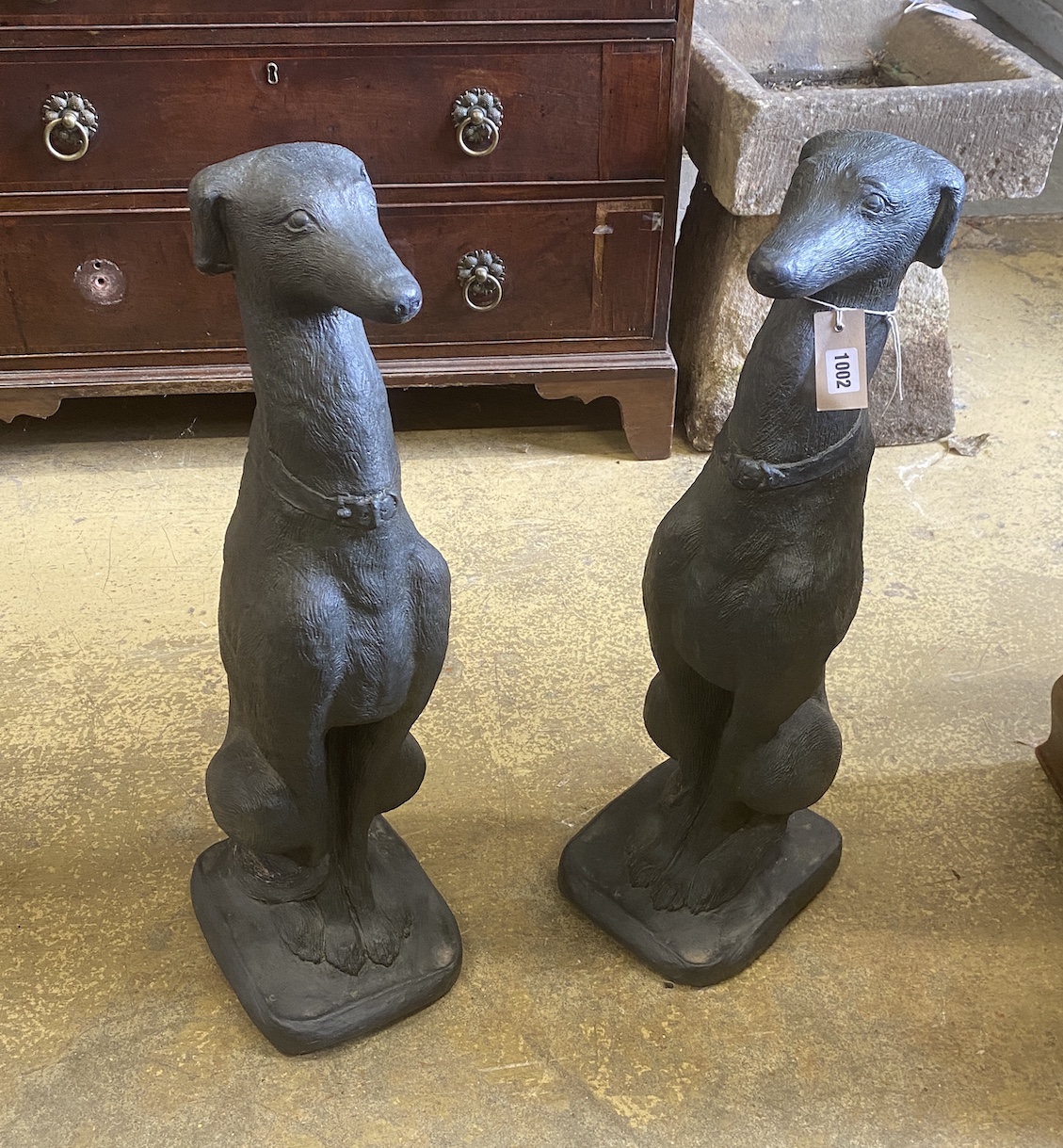 A pair of painted cast stone seated greyhound garden ornaments, height 74cm